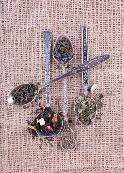 Tee in Löffeln auf Sacktuch Stoff Hintergrund — Stockfoto