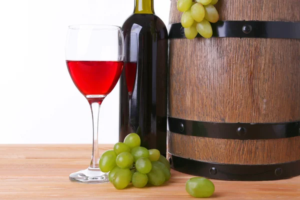 Şarap kadehi ve şişe, üzüm ve beyaz zemin üzerine ahşap masa üzerinde varil Telifsiz Stok Imajlar