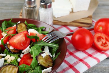Patlıcan salata domates, roka ve beyaz peynir, peçeteye renk ahşap arka plan üzerinde