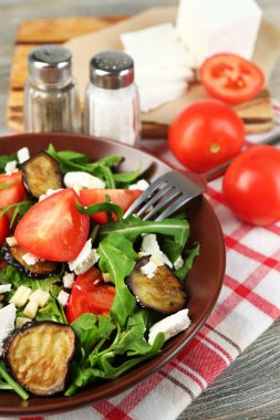 Patlıcan salata domates, roka ve beyaz peynir, peçeteye renk ahşap arka plan üzerinde