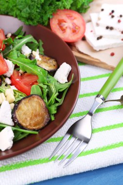 Patlıcan salata domates, roka ve beyaz peynir, peçeteye renk ahşap arka plan üzerinde