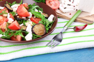 Patlıcan salata domates, roka ve beyaz peynir, peçeteye renk ahşap arka plan üzerinde