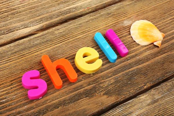 Shell word formed with colorful letters on wooden background — Stock Photo, Image