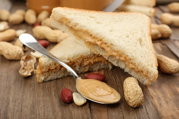 Bread slices with creamy peanut butter on wooden table — Stock Photo, Image