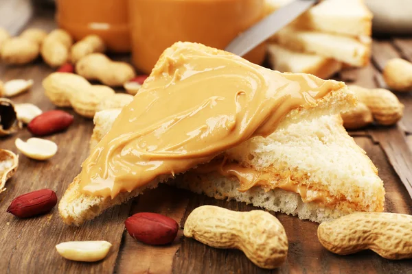 Bread slices with creamy peanut butter on wooden table — Stock Photo, Image