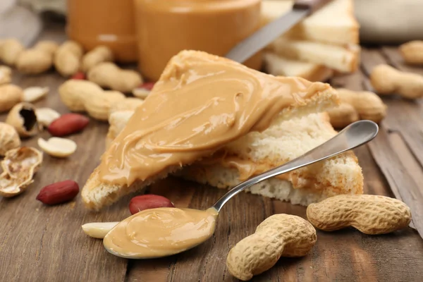 Bread slices with creamy peanut butter on wooden table — Stock Photo, Image