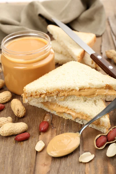 Fatias de pão com manteiga de amendoim cremosa na mesa de madeira — Fotografia de Stock