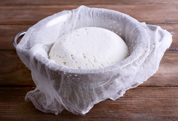 Queso de cabaña sobre gasa en colador sobre fondo de madera — Foto de Stock