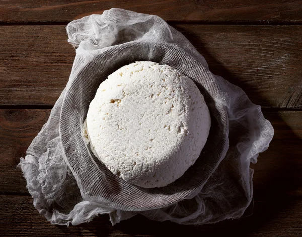 Cottage cheese on gauze in colander on wooden background — Stock Photo, Image