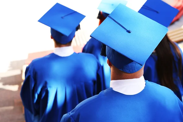 Estudantes de graduação vestindo chapéu e vestido de formatura, ao ar livre — Fotografia de Stock