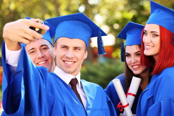 Estudantes de graduação vestindo chapéu e vestido de formatura, ao ar livre — Fotografia de Stock