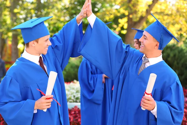 Yüksek lisans öğrencileri mezuniyet şapka ve elbise, açık havada giyiyor — Stok fotoğraf