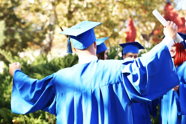 Estudantes de graduação vestindo chapéu e vestido de formatura, ao ar livre — Fotografia de Stock