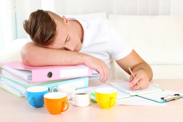 Uomo stanco con molte cartelle dorme sul tavolo — Foto Stock