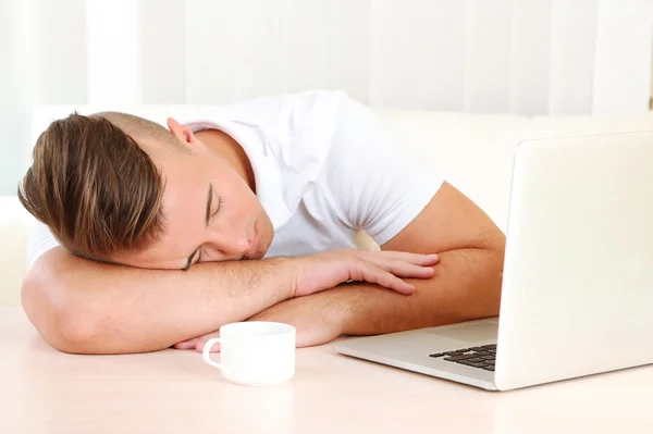 Cansado homem com notebook dorme na mesa — Fotografia de Stock