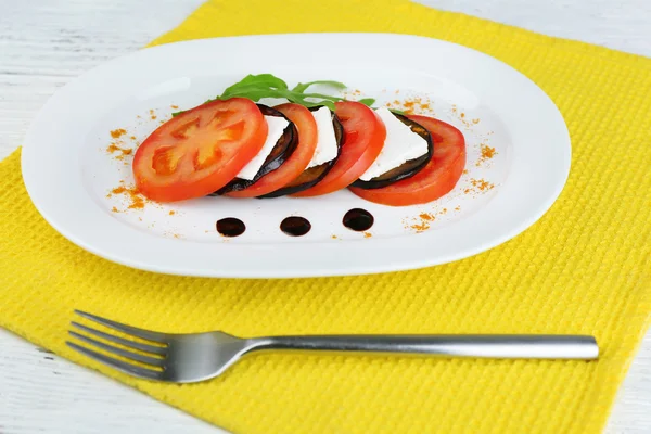 Lilku salát s rajčaty a balkánským sýrem na talíři, na dřevěné pozadí — Stock fotografie