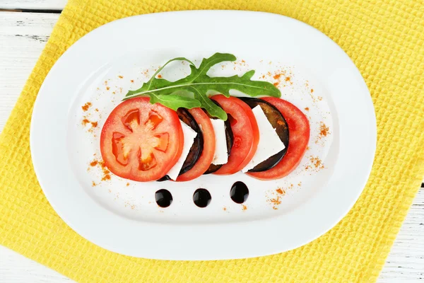 Eggplant salad with tomato and feta cheese on plate, on wooden background — Stock Photo, Image