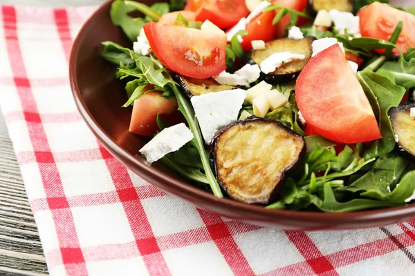 Salada de berinjela com tomate, rúcula e queijo feta, no guardanapo, na cor de fundo de madeira — Fotografia de Stock