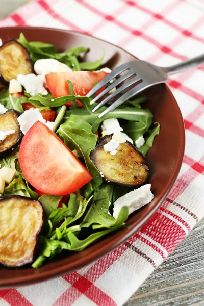 Ensalada de berenjena con tomates, rúcula y queso feta, en servilleta, sobre fondo de madera de color — Foto de Stock