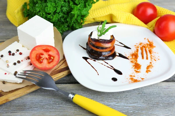 Äggplanta sallad med tomater och fetaost på plattan, Servett, på trä bakgrund — Stockfoto