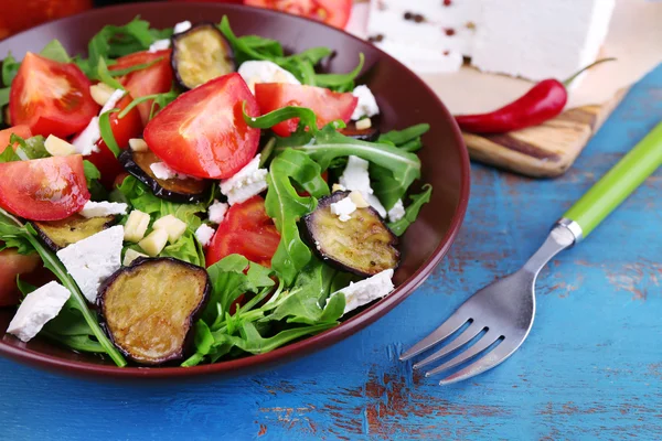 Ensalada de berenjena con tomates, rúcula y queso feta, en servilleta, sobre fondo de madera de color —  Fotos de Stock