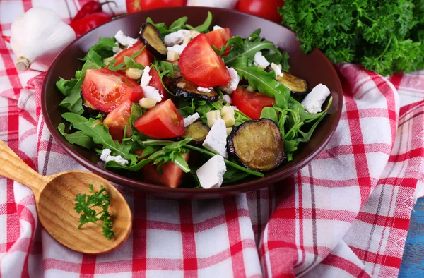 Lilku salát s rajčaty, rukolou a sýrem feta sýr, na ubrousek, na barevné dřevěné pozadí — Stock fotografie