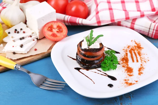 Ensalada de berenjena con tomates y queso feta en plato, en servilleta, sobre fondo de madera — Foto de Stock