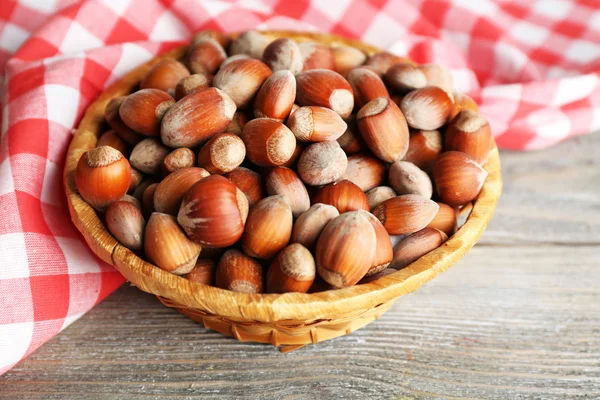 Hazelnuts in wicker basket on wooden background — Stock Photo, Image