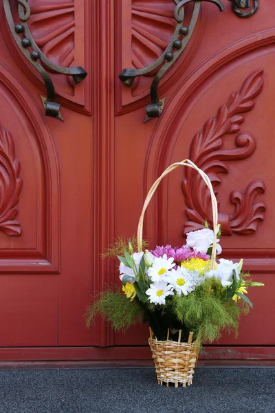 Kwiaty w koszyku na tle drewniane drzwi — Zdjęcie stockowe