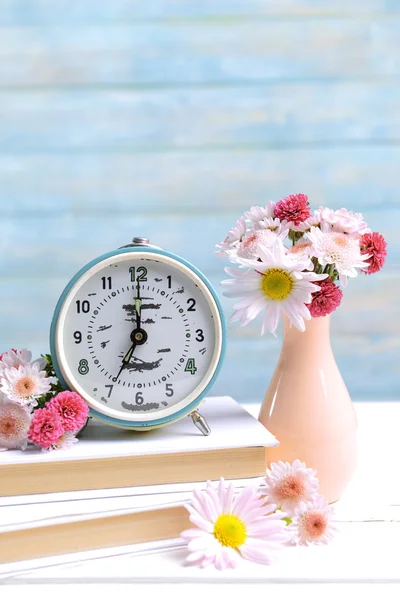 Beautiful flowers in vase on table on light blue background