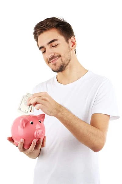 Knappe jongeman met piggy bank geïsoleerd op wit — Stockfoto