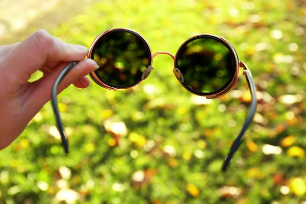 Glasses in hand on green grass background — Stock Photo, Image