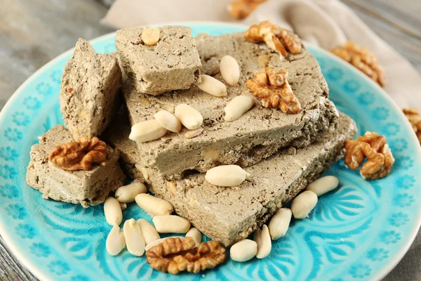 Sunflower halva with nuts on plate, on wooden background — Stock Photo, Image