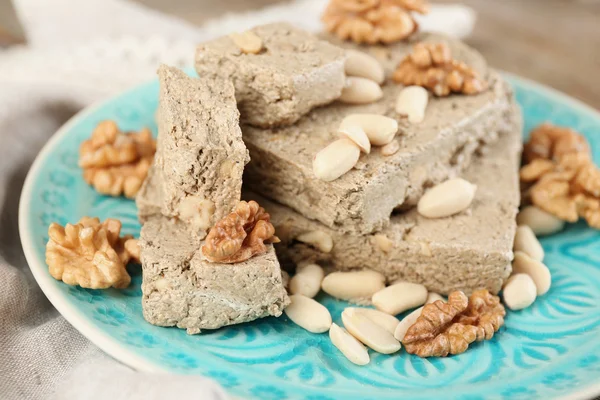 Zonnebloem halva met noten op plaat, op houten achtergrond — Stockfoto