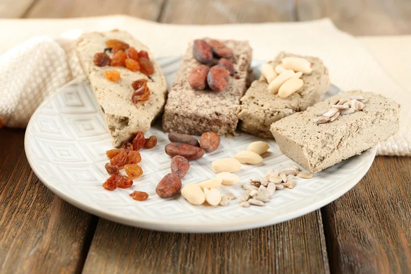 Sortimento de halva de girassol na placa, no fundo de madeira — Fotografia de Stock