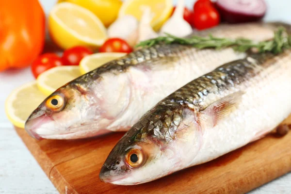 Свіжа сира риба та харчові інгредієнти на столі — стокове фото