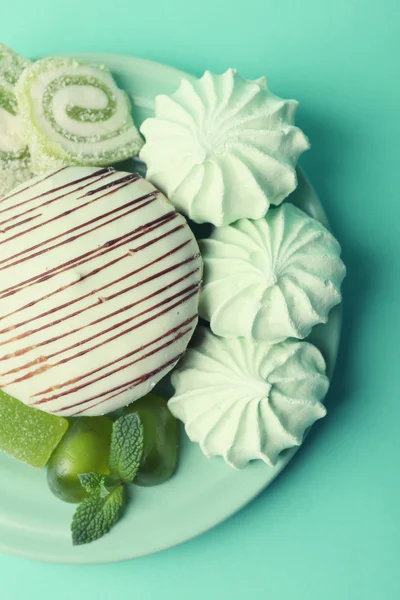 Meringues de couleur menthe, bonbons à la menthe et gâteau savoureux sur fond de couleur — Photo