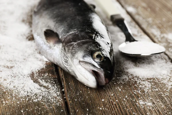 Peixe fresco e sal em colher no fundo de madeira — Fotografia de Stock