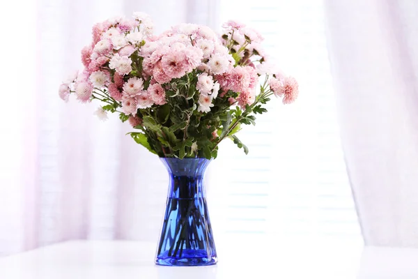 Mooie bloemen in vaas met licht uit raam — Stockfoto