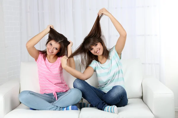 Schöne Mädchen Zwillinge sitzen auf Sofa im Zimmer — Stockfoto