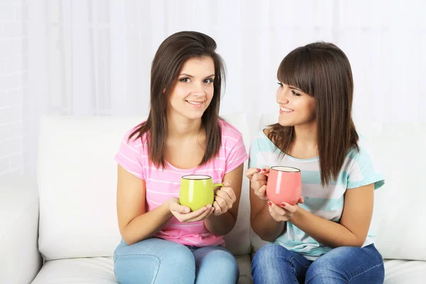 Beautiful girls twins drinking tea at home — Stock Photo, Image