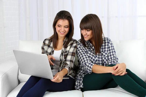 Schöne Mädchen Zwillinge sitzen auf Sofa mit Notizbuch — Stockfoto