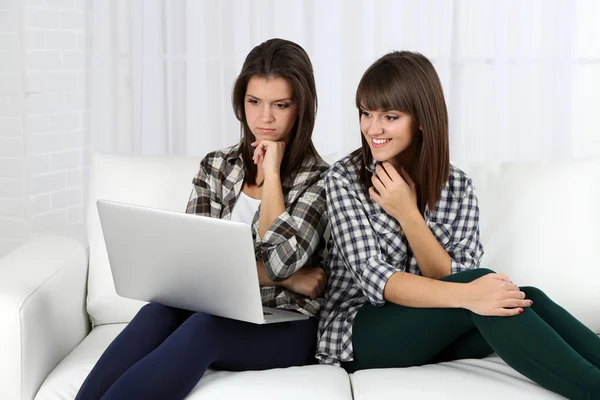 Schöne Mädchen Zwillinge sitzen auf Sofa mit Notizbuch — Stockfoto