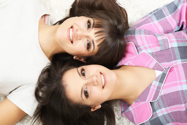 Beautiful girls twins in pajamas lie on carpet — Stock Photo, Image