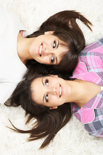 Mooie meisjes tweeling in pyjama's liggen op tapijt — Stockfoto