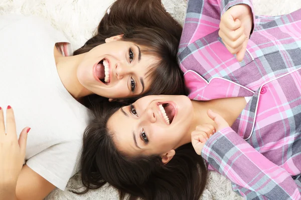 Piękne dziewczyny bliźniaków w piżamie leżą na dywanie — Zdjęcie stockowe
