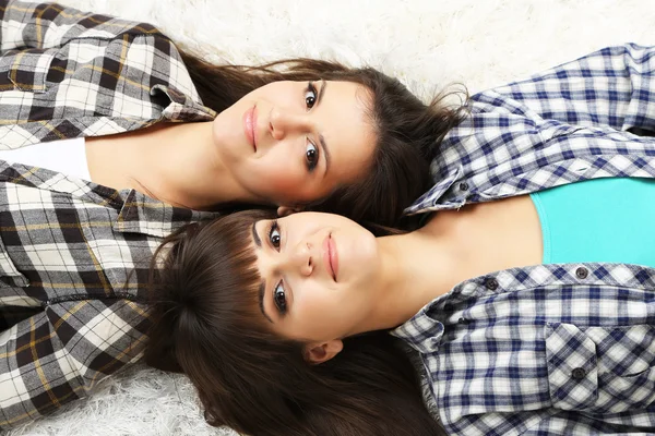 Beautiful girls twins in pajamas lie on carpet — Stock Photo, Image