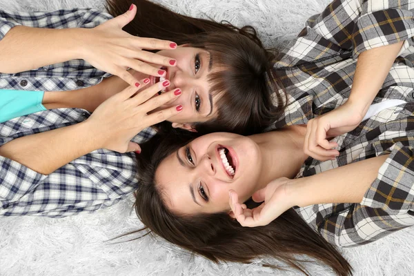 Piękne dziewczyny bliźniaków w piżamie leżą na dywanie — Zdjęcie stockowe