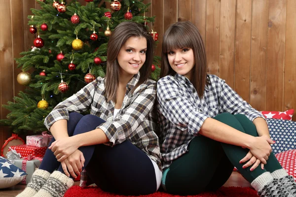 Beautiful girls twins near Christmas tree at home — Stock Photo, Image