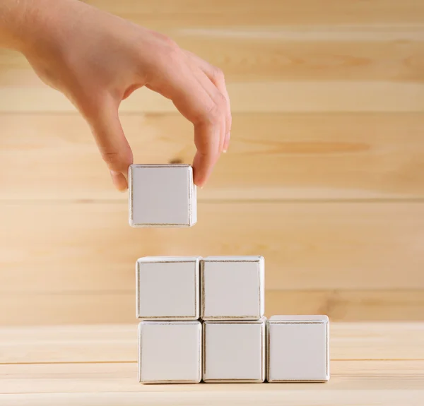 Cubo educativo in mano, su sfondo di legno — Foto Stock